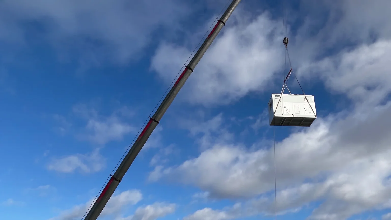 Air conditioning unit suspended from a crane during a lift